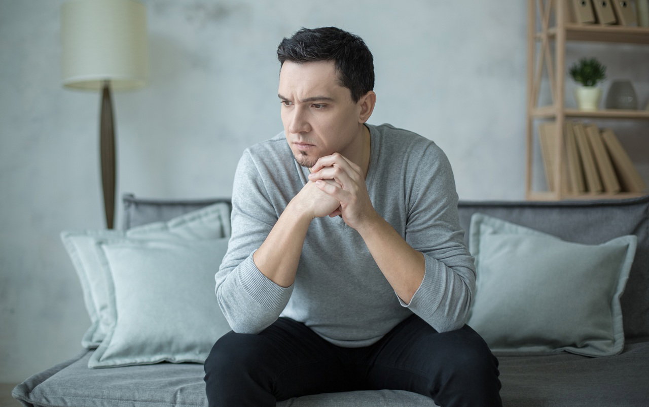 mężczyzna w wieku 30 plus siedzi na kanapie zamyślony