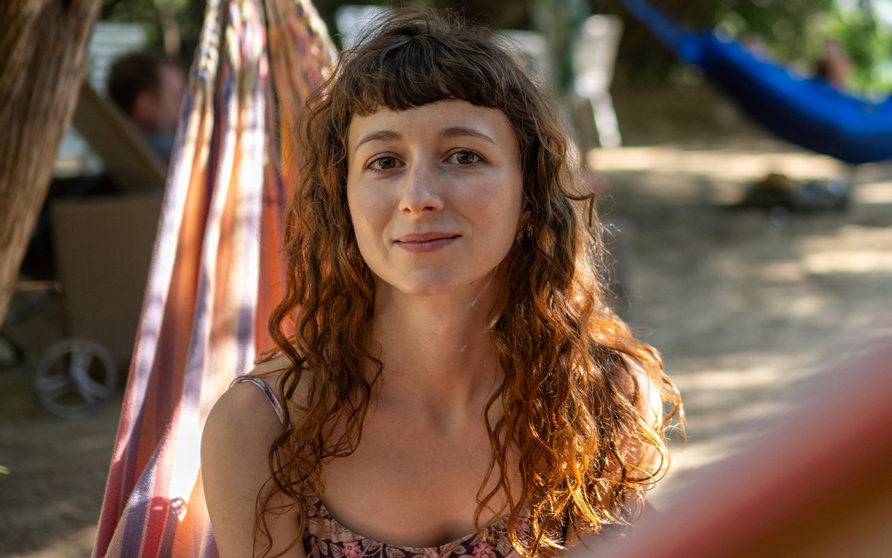 kobieta w wieku 25 plus siedzi na hamaku i nieśmiało się uśmiecha