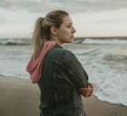 kobieta w wieku 30 plus blondynka stoi na plaży i patrzy na morze zamyślona