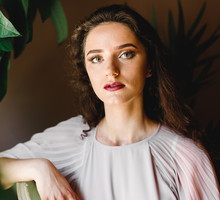 kobieta w wieku 30 plus elegancka siedzi przy zielonej roślinie zamyślona i wystraszona