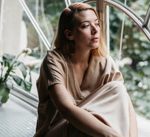 kobieta w wieku 30 plus siedzi przy oknie smutna i zamyślona