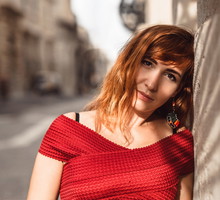 kobieta w wieku 30 plus w czerwonej sukience stoi na ulicy włoskiego miasta rozmarzona