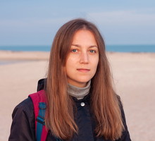 kobieta w wieku 30 plus z długimi włosami stoi na plaży zamyślona