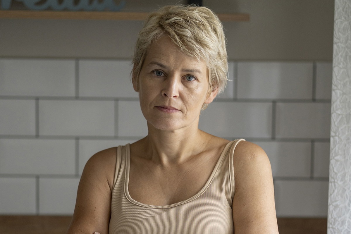 kobieta w wieku 45 plus blondynka stoi na tle kuchni zmartwiona