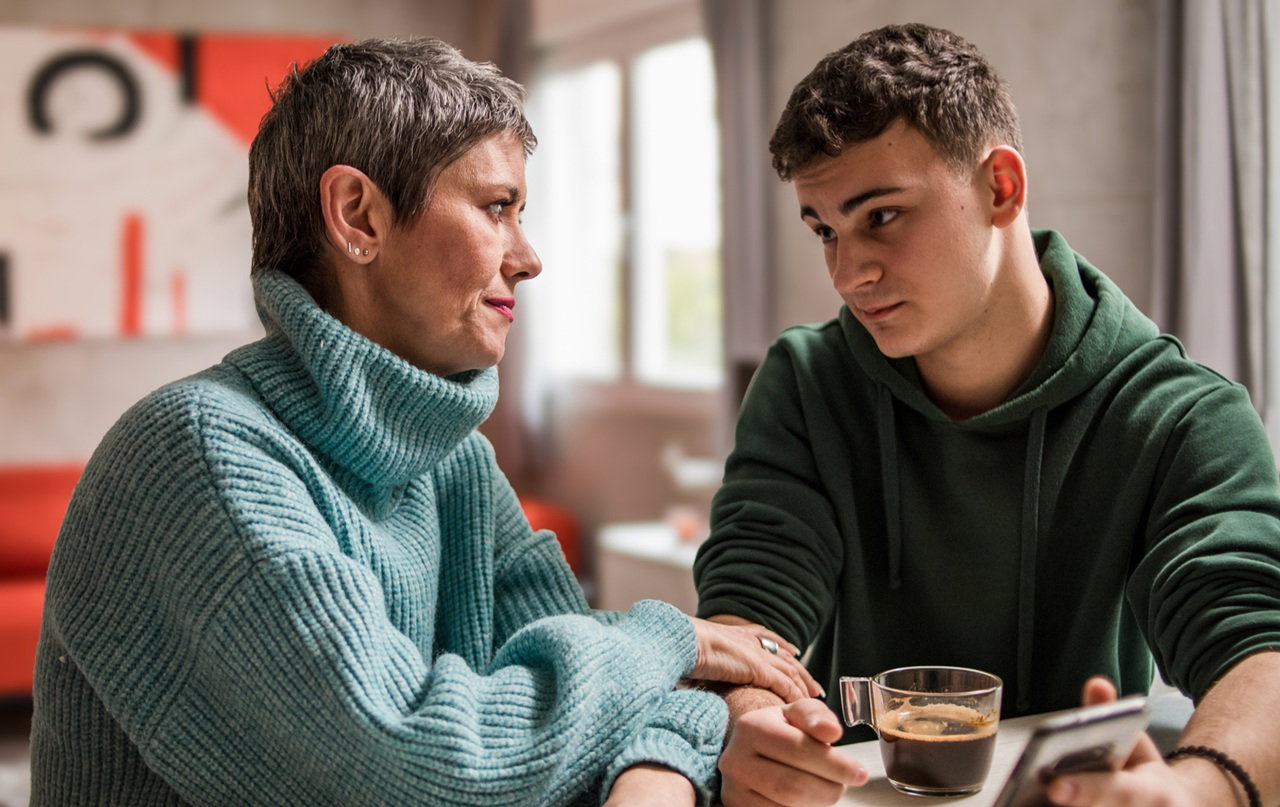 kobieta  w wieku 45 plus rozmawia z synem  w wieku 18+ w zielonej bluzie