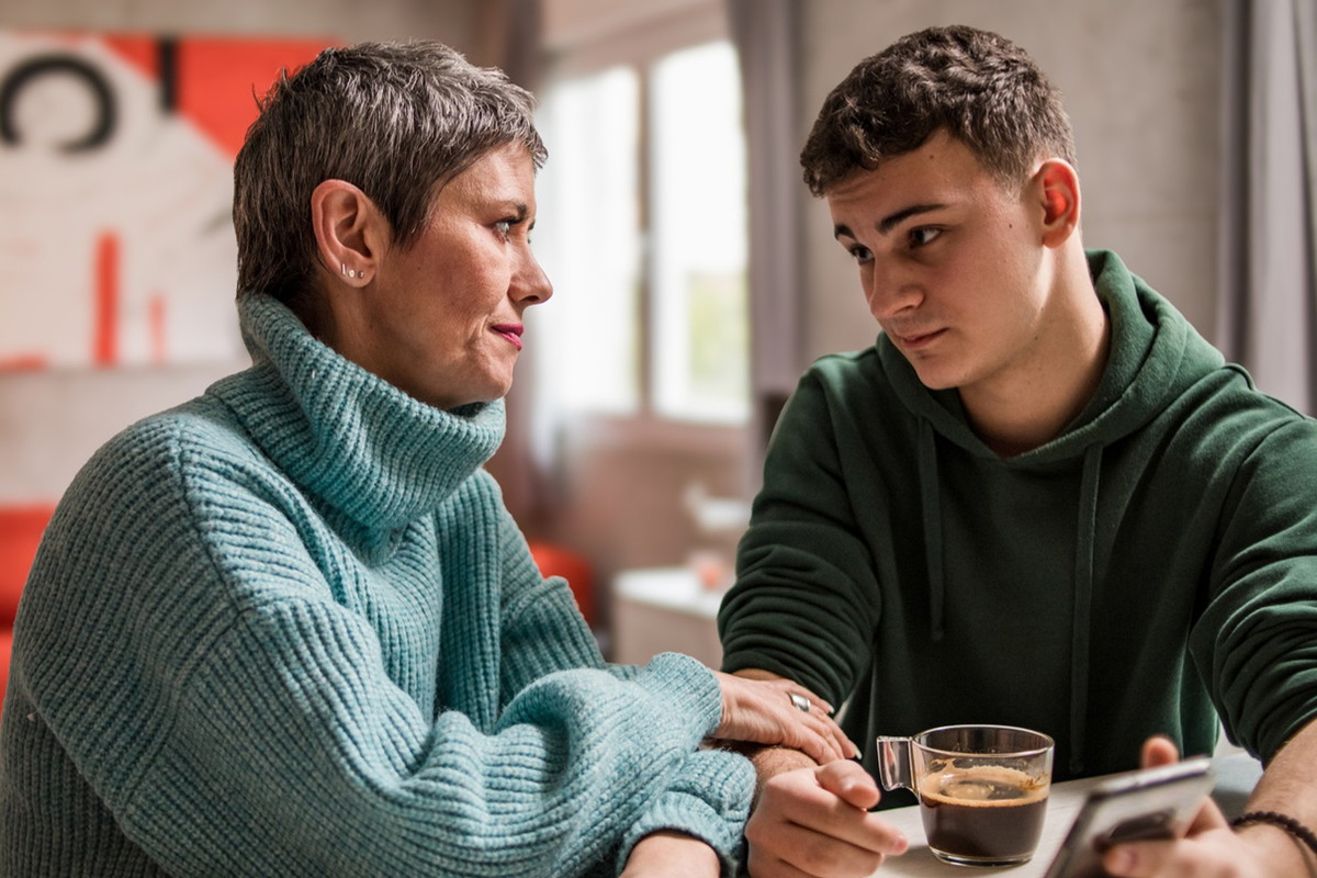 kobieta w wieku 45 plus rozmawia z synem w wieku 18+ w zielonej bluzie