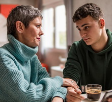 kobieta w wieku 45 plus rozmawia z synem w wieku 18+ w zielonej bluzie