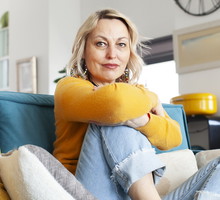 kobieta w wieku 50 plus blondynka siedzi na kanapie z poważną miną
