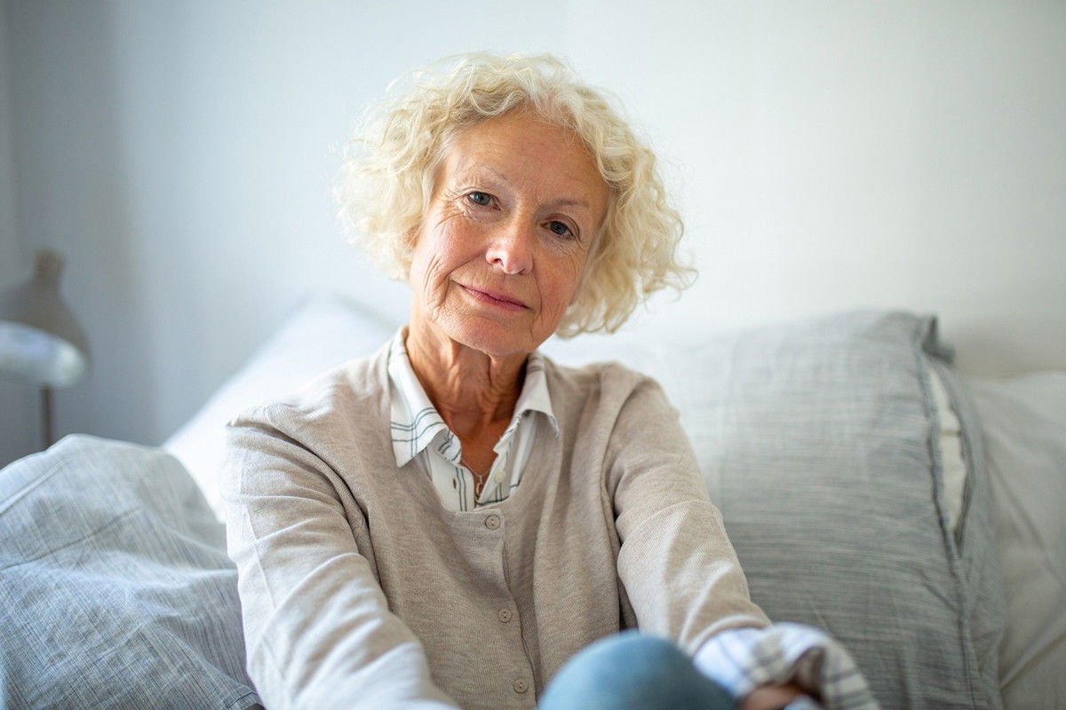 kobieta w wieku 60 plus blond włosy siedzi na kanapie z poważną miną
