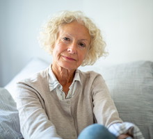 kobieta w wieku 60 plus blond włosy siedzi na kanapie z poważną miną