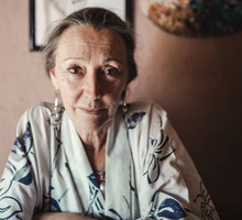kobieta w wieku 60 plus siedzi przy stole w szlafroku ze smutną miną