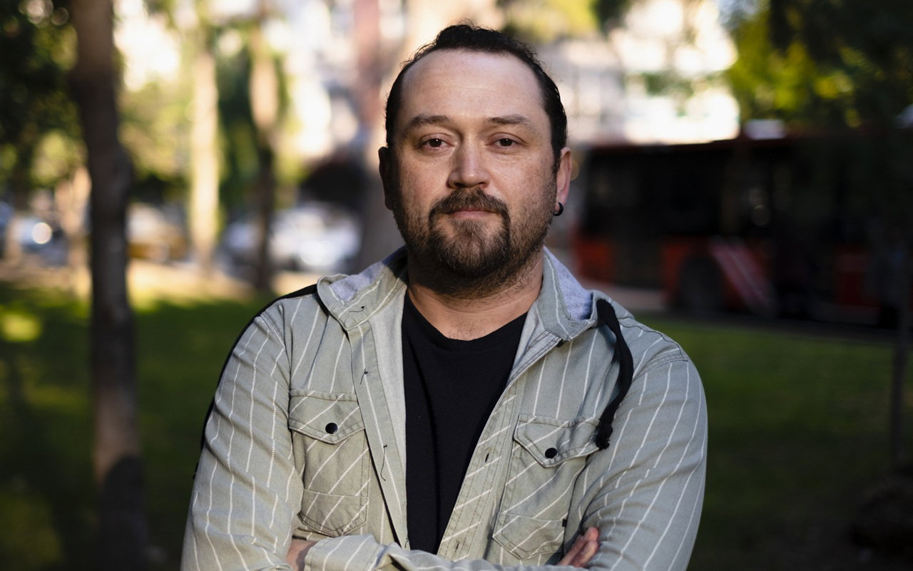 mężczyzna w wieku 30 plus stoi na tle drzew z poważną miną