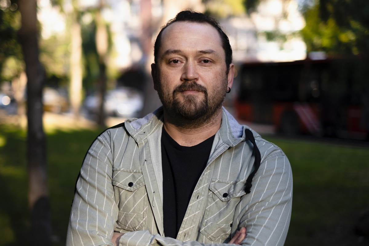 mężczyzna w wieku 30 plus stoi na tle drzew z poważną miną