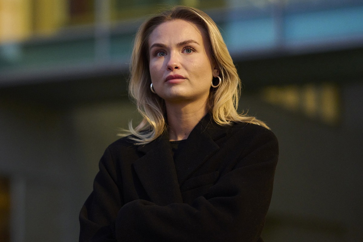 kobieta w wieku 30 plus blondynka stoi na tle biurowca z poważną miną
