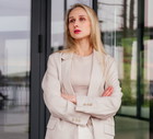 kobieta w wieku 30 plus blondynka stoi na tle szklanych drzwi budynku smutna