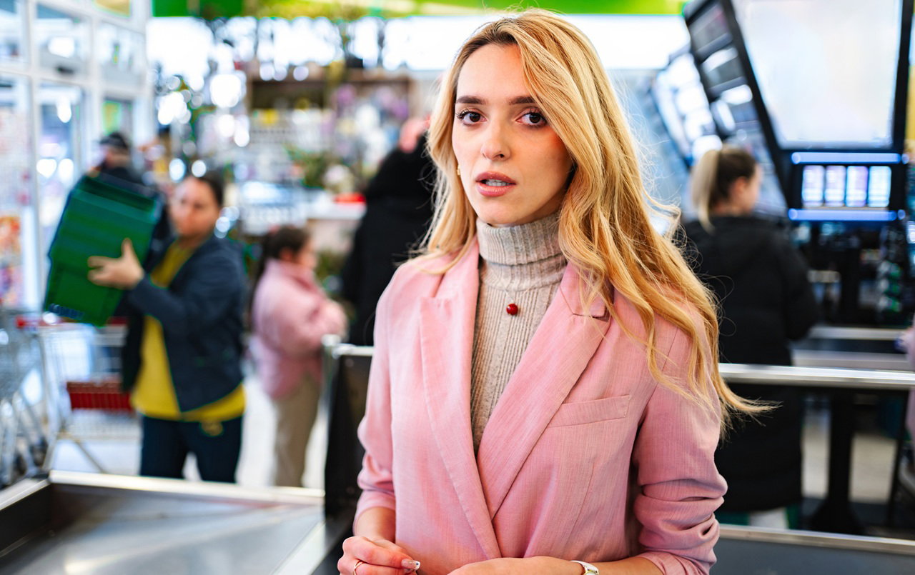 kobieta w wieku 30 plus blondynka stoi w supermarkecie z przerażoną miną