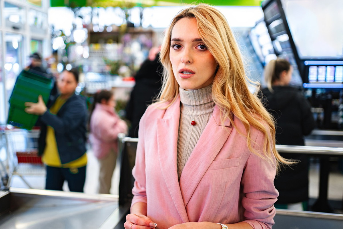 kobieta w wieku 30 plus blondynka stoi w supermarkecie z przerażoną miną