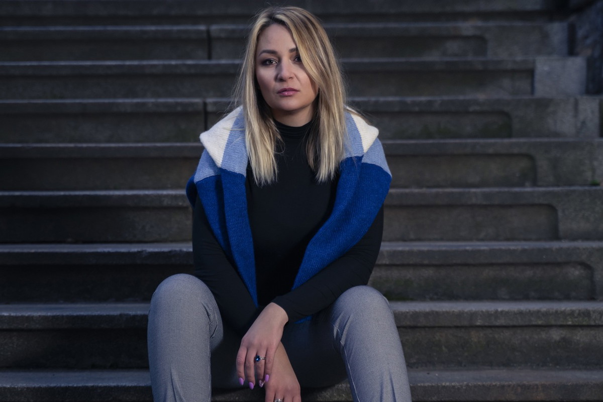 kobieta w wieku 30 plus blondynka ze swetrem na ramionach siedzi na schodach smutna i zrezygnowana