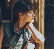 kobieta w wieku 30 plus z grzywką siedzi na tarasie i patrzy zamyślona w dal