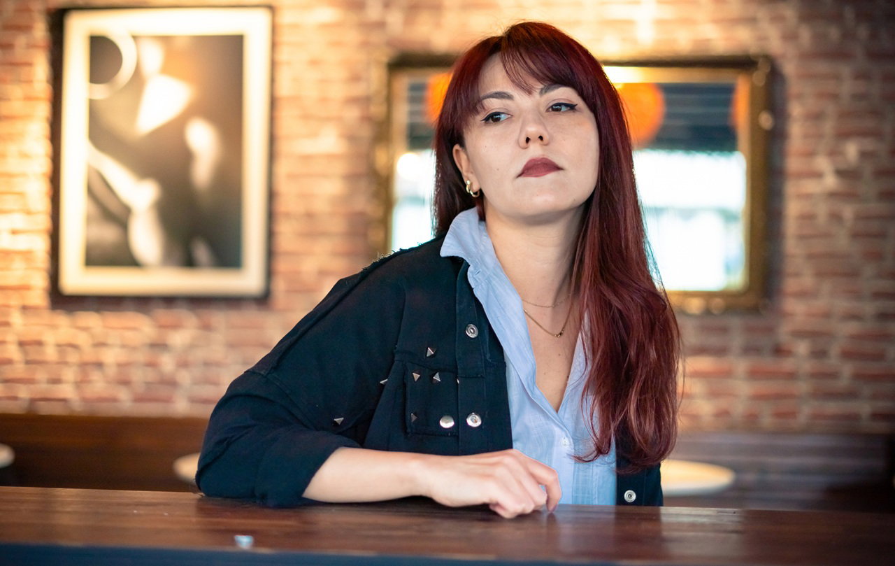 kobieta w wieku 30 plus z kasztanowymi długimi włosamisiedzi w restauracji ze zdegustowaną miną na tle ściany z obrazami