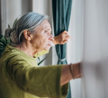 kobieta wyglądająca przez okno na ogród