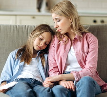 mama w wieku 30 plus i córka w wieku 7 plus siedzą na kanapie smutne i zamyślone