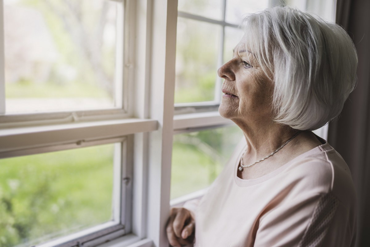 seniorka wyglądająca przez okno