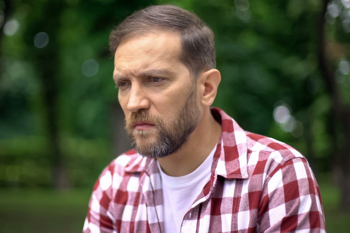 Zamyślony mężczyzna na tle drzew