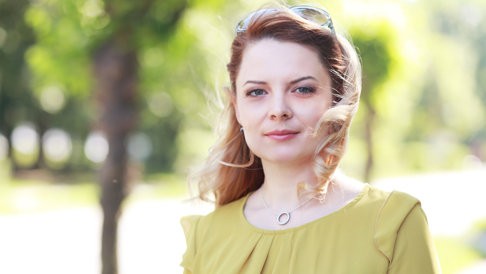kobieta w wieku 30 plus blondynka w żółtej sukience stoi na ulicy z poważną miną