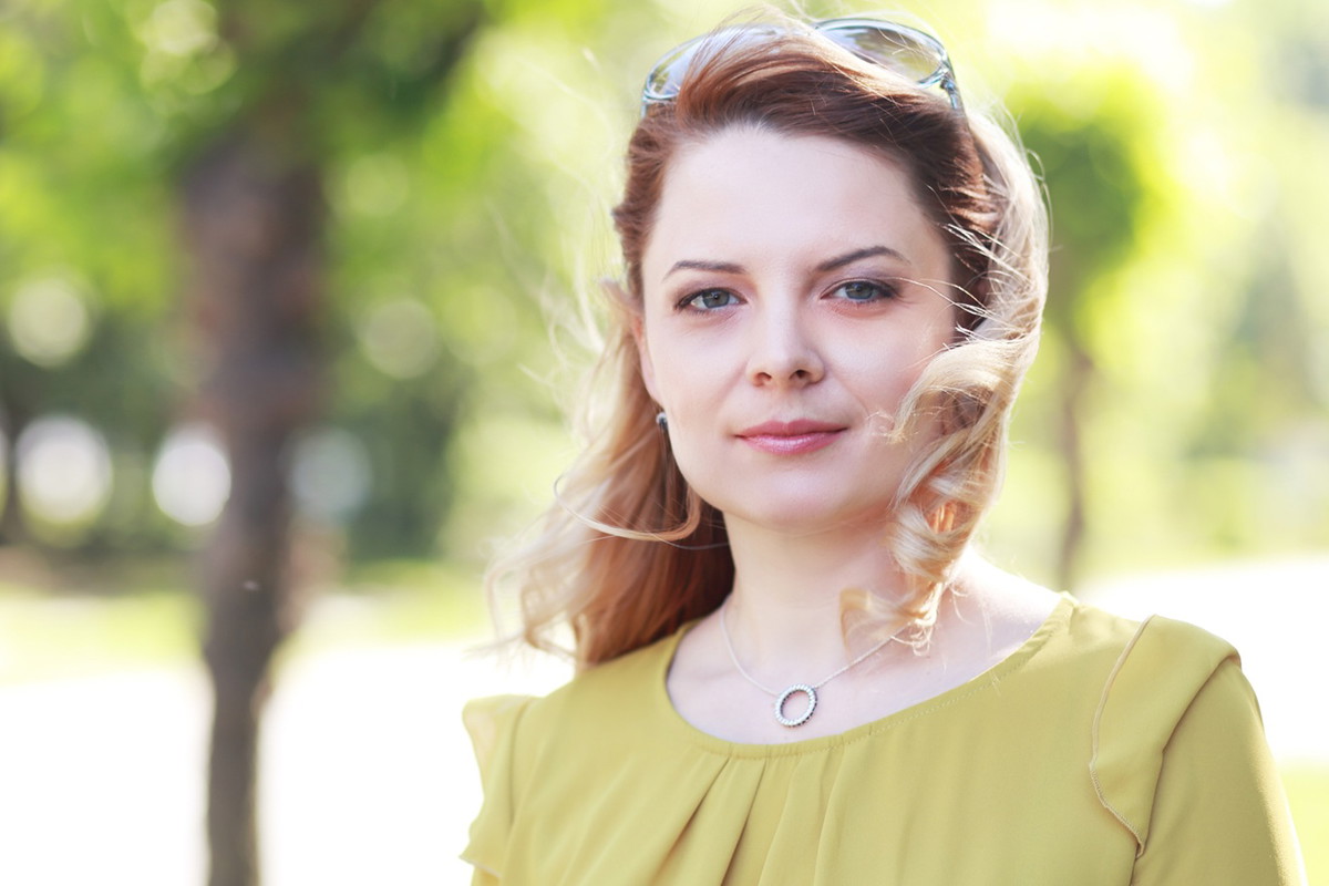 kobieta w wieku 30 plus blondynka w żółtej sukience stoi na ulicy z poważną miną