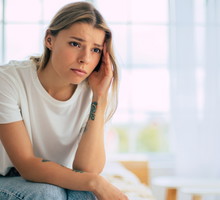 kobieta w wieku 25 plus blondynka w białym t-shircie siedzi w pokoju ze zmartwioną miną