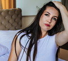 kobieta w wieku 30 plus z długimi ciemnymi włosami siedzi w pokoju i trzyma się za głowę z poważną miną