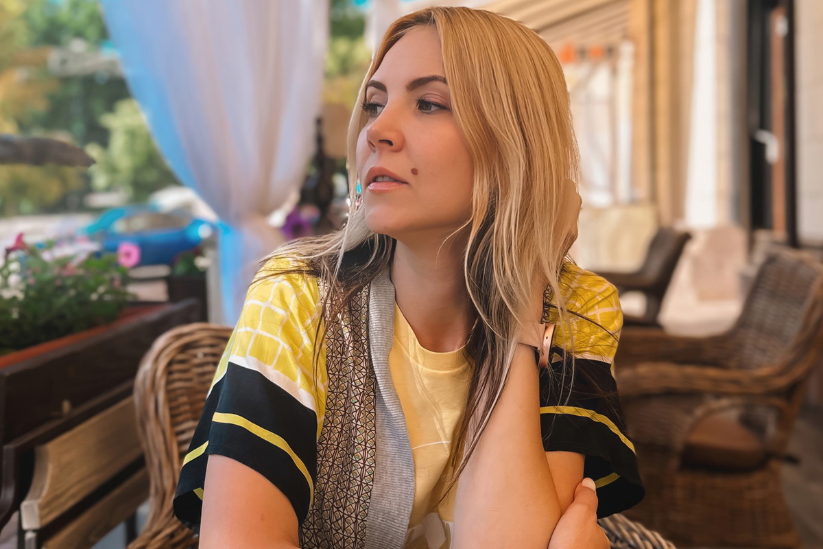 kobieta w wieku 35 plus blondynka patrzy zamyślona i smutna w dal na kawiarnianym tarasie