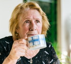 kobieta w wieku 70 plus siedzi przy stole w kuchni i pije herbatę zamyślona i smutna