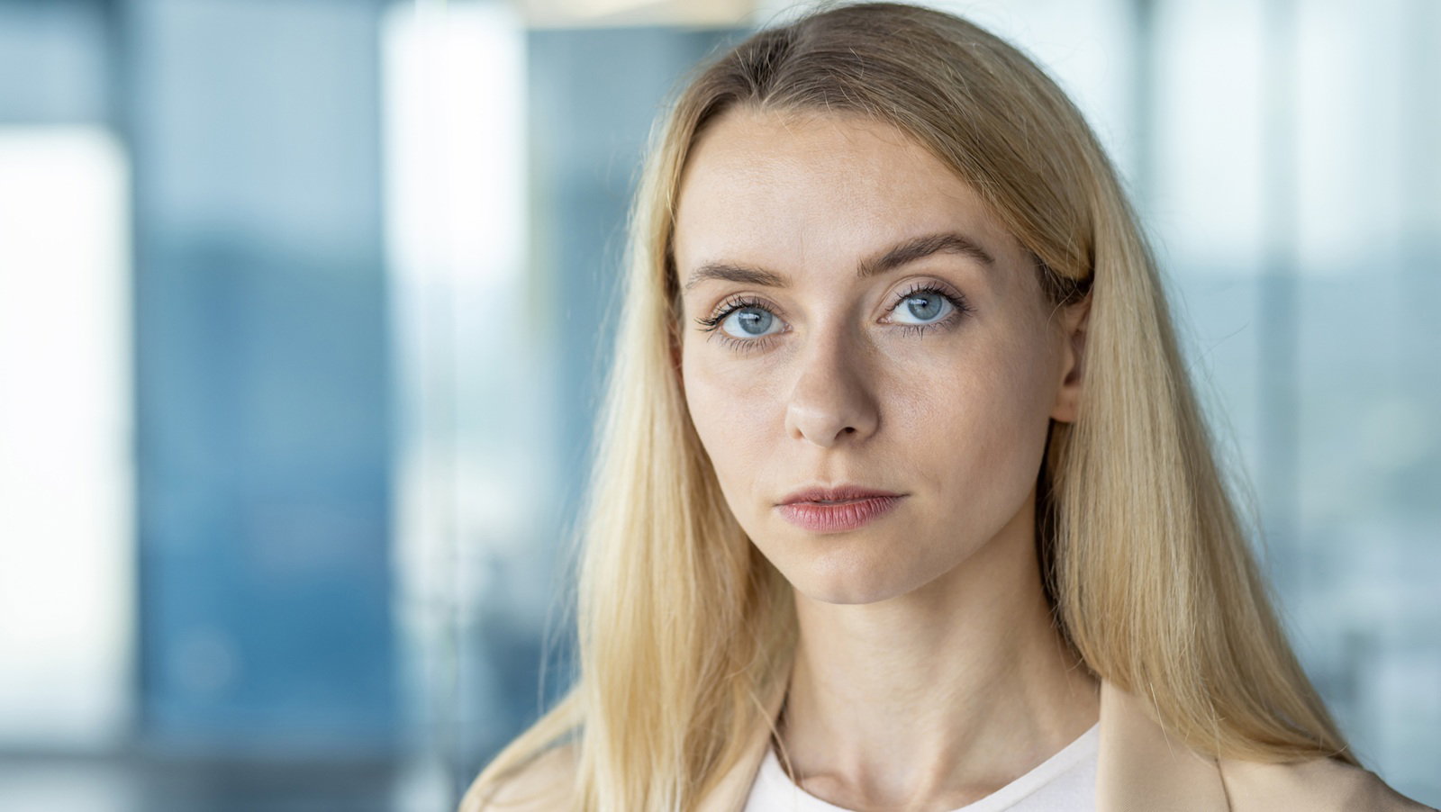 młoda kobieta blondynka 30 plus stoi na tle galerii handlowej z poważną miną zawiedziona