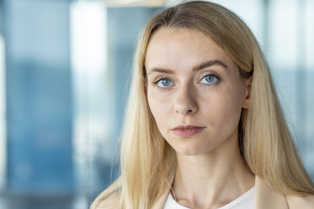 młoda kobieta blondynka 30 plus stoi na tle galerii handlowej z poważną miną zawiedziona