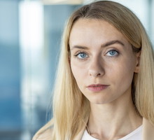 młoda kobieta blondynka 30 plus stoi na tle galerii handlowej z poważną miną zawiedziona