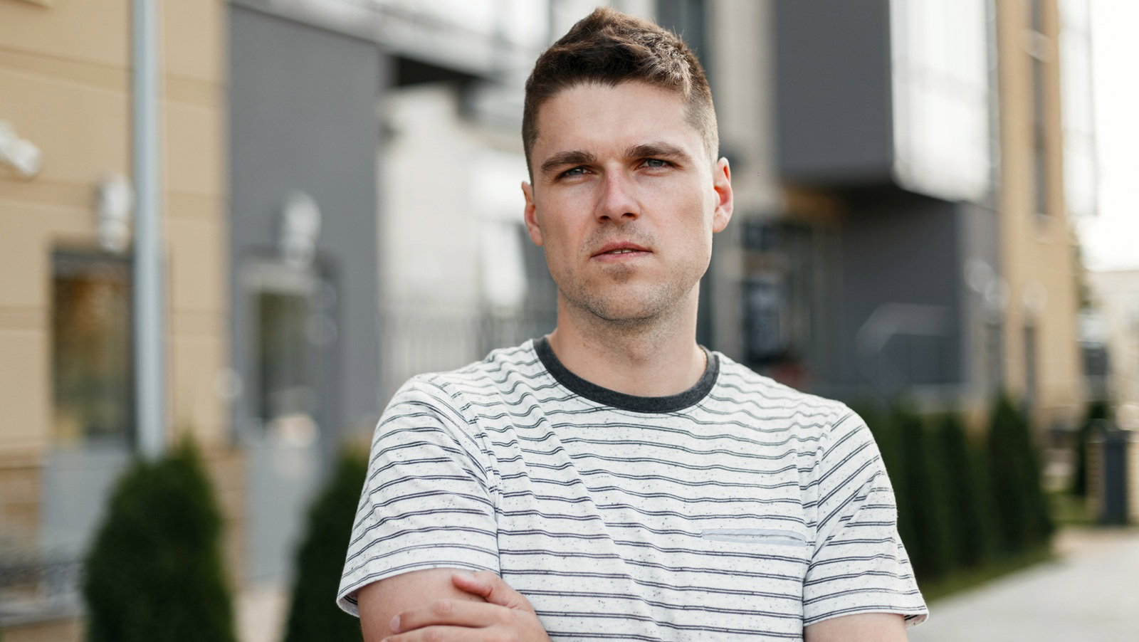 młody mężczyzna w wieku 30 plus w t-shircie w paski stoi na ulicy z poważną zafrasowaną miną