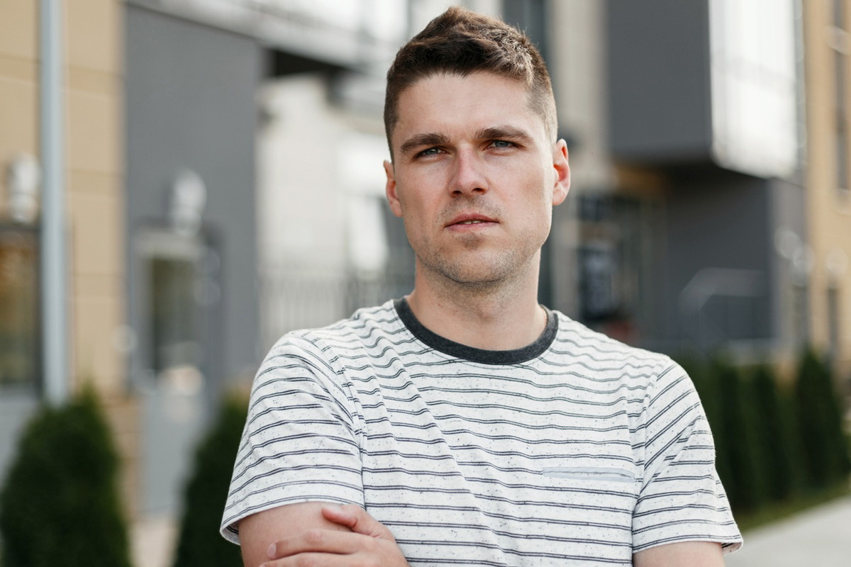 młody mężczyzna w wieku 30 plus w t-shircie w paski stoi na ulicy z poważną zafrasowaną miną