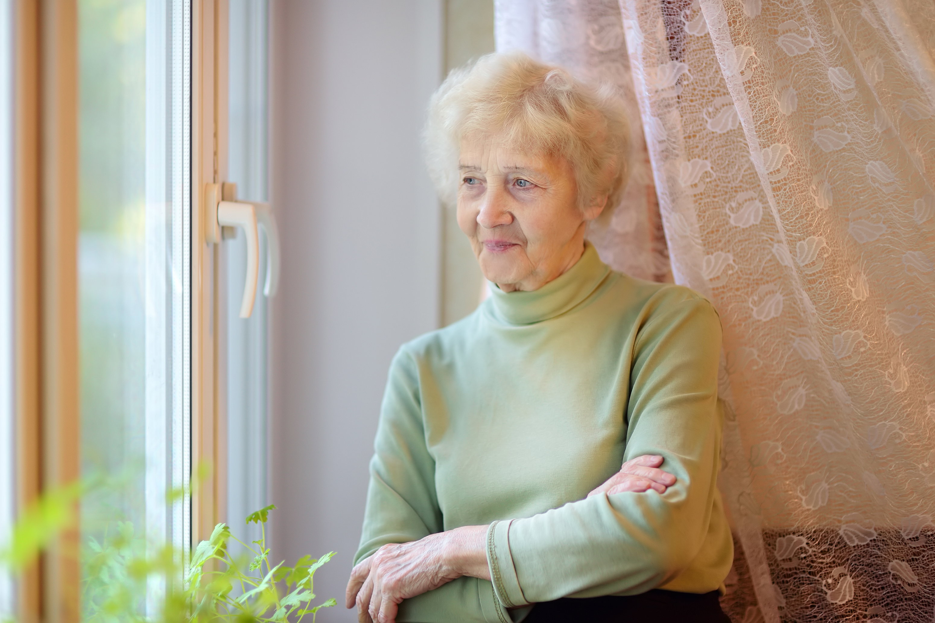 seniorka stojąca w oknie