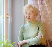seniorka stojąca w oknie