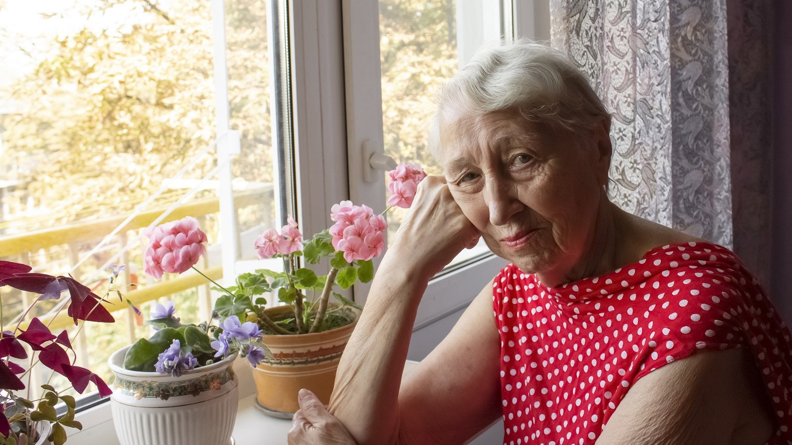 zamyślona seniorka przy parapecie