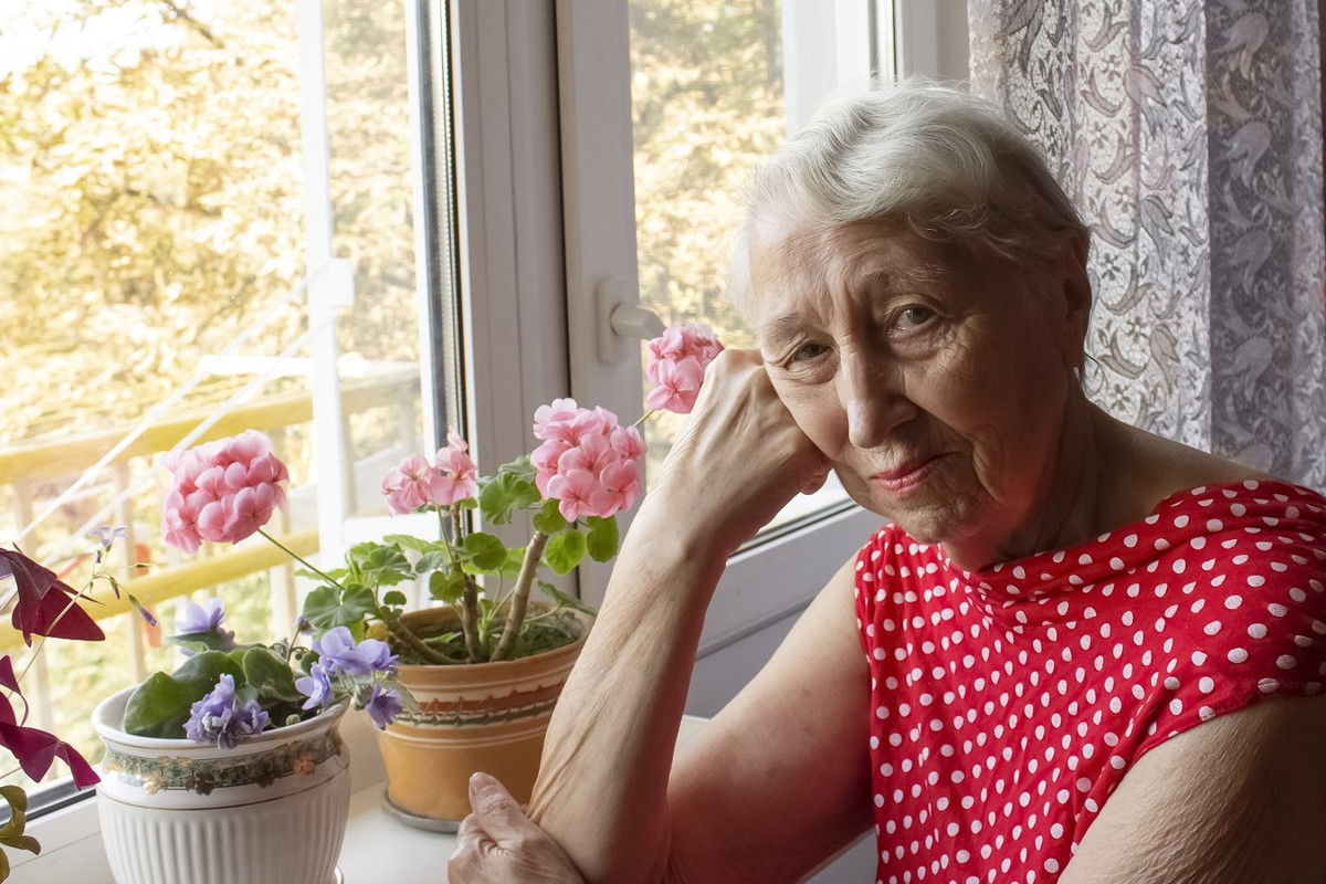 zamyślona seniorka przy parapecie