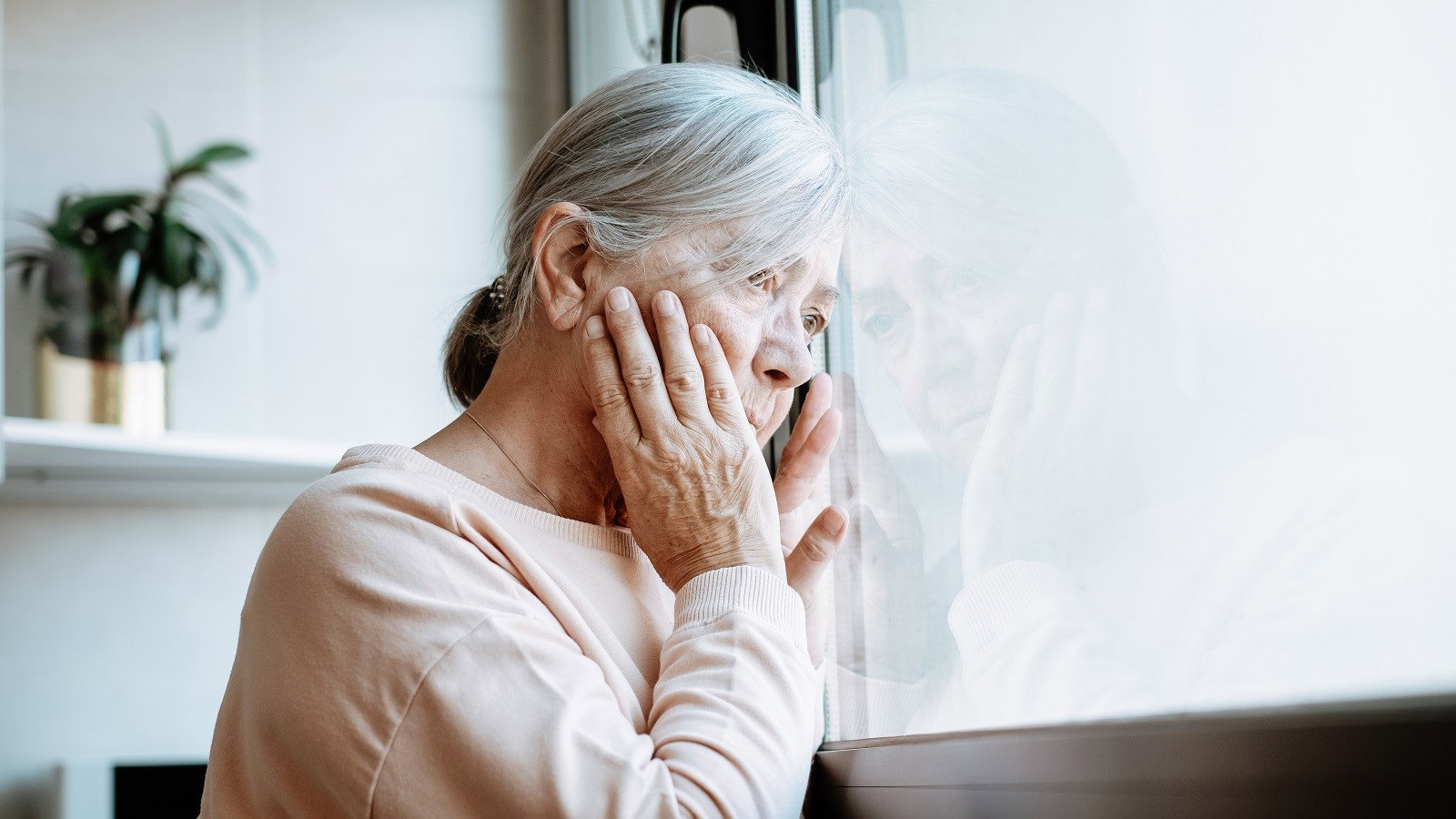 zmartwiona seniorka w oknie
