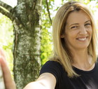 kobieta w wieku 30 plus blondynka z długimi włosami w czarnej koszulce stoi w brzeźniaku i się śmieje