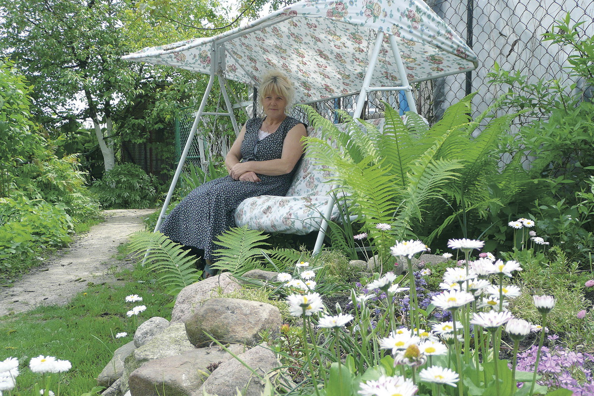 Bujana huśtawka ma jasne, kwieciste obicie, dzięki czemu nie wyróżnia się zbyt mocno na tle ogrodowej scenerii