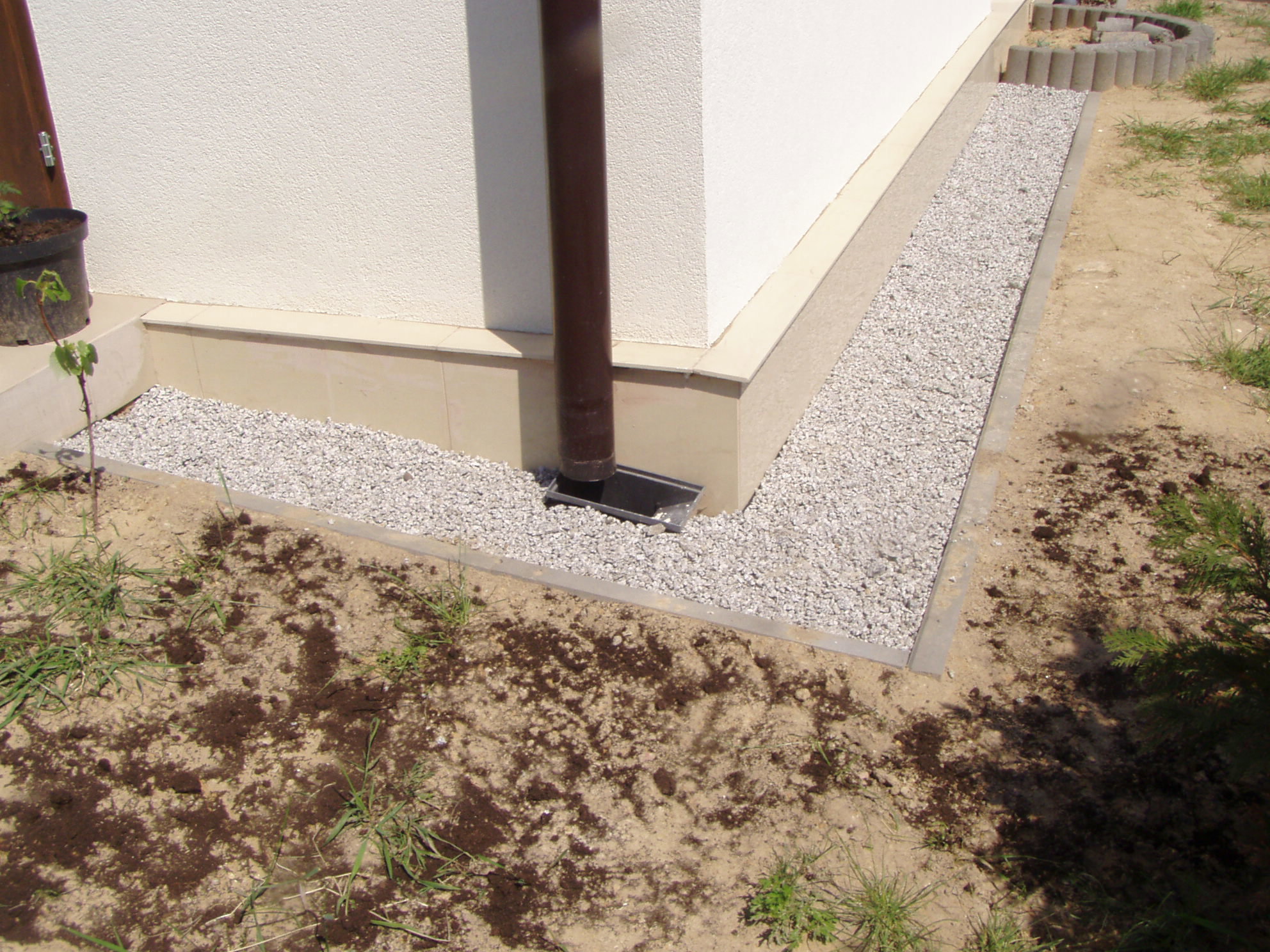 Jeśli pod kamieniami usypiemy warstwę piasku, woda spływająca z rynny szybciej będzie wsiąkała do gruntu.