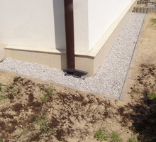 Jeśli pod kamieniami usypiemy warstwę piasku, woda spływająca z rynny szybciej będzie wsiąkała do gruntu.