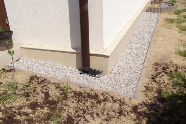 Jeśli pod kamieniami usypiemy warstwę piasku, woda spływająca z rynny szybciej będzie wsiąkała do gruntu.