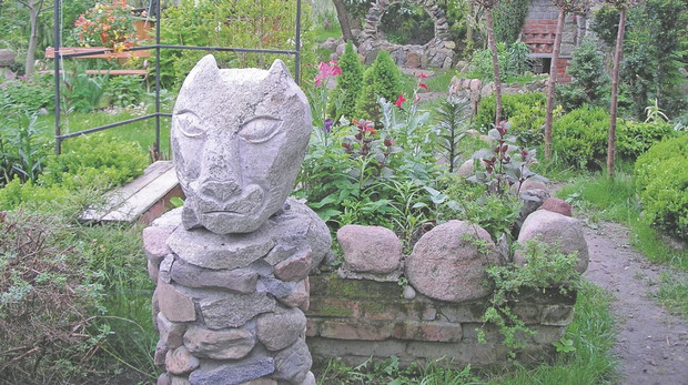 „Kamienne głowy porozmieszczałem w różnych częściach posesji. Na pierwszym planie zdjęcia widać rzeźbę 'Ogrodowy Strażnik', a w tle – murek-słoneczko”.
